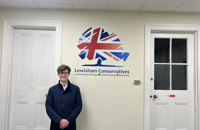 Hugh Rees-Beaumont standing next to a Lewisham Conservatives sign.